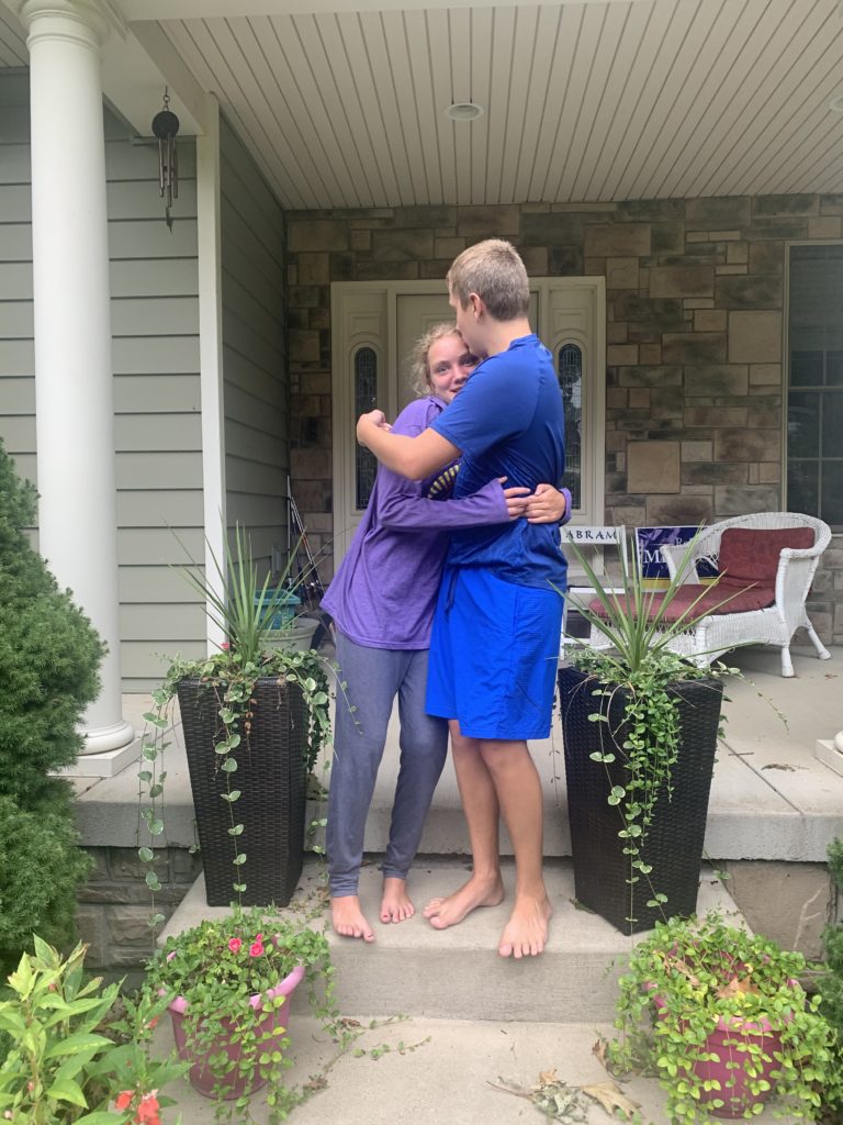 Abram and Maci hugging on their front step before the first day of school